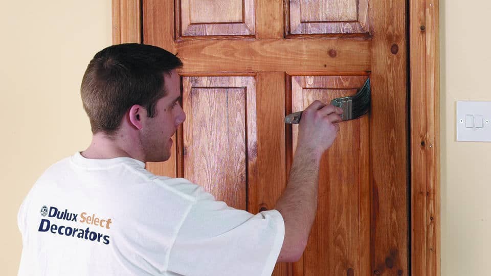 man painting a door in ici paints branded shirt