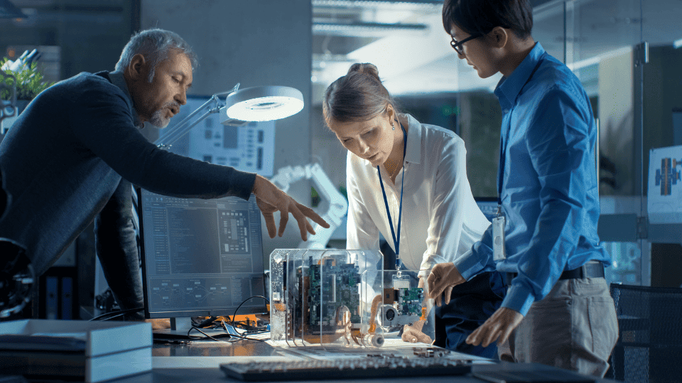 Two men and a woman looking at computer circuit boards